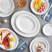 A table with Acopa white oval platters filled with food including fruit and pie.