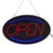 An oval LED open sign with lights on it hanging on a wall.