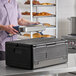 A black insulated food pan carrier with a flip-down top, designed for holding full-size pans up to 8 inches deep.