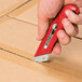 A person using a red Pacific Handy Cutter to cut a box.