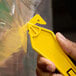 A hand holding a yellow Pacific Handy Cutter EZST all-purpose cutter to cut a plastic bag.
