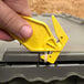 A hand holding a yellow Pacific Handy Cutter to open a box.