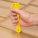 A hand holding a yellow Pacific Handy Cutter EZST on a box.