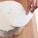 A hand using an Ateco baking / icing spatula to spread frosting on a cake.