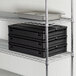 A black plastic CaterGator food pan carrier with a metal shelf holding a black food pan.