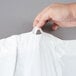 A hand holding a plastic hotel laundry bag with a white drawstring.