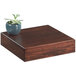 A Cal-Mil square walnut wood riser with a plant on it.