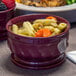 A Dinex cranberry insulated bowl filled with food on a table.