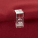 A clear plastic Snap Drape table skirt clip on a red fabric.