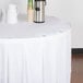 A white table with a white tablecloth and Snap Drape LV clear plastic table skirt clips on it.