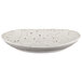 An oval white melamine plate with black speckled spots.