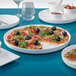 A white Villeroy & Boch porcelain platter with a pizza topped with olives and tomatoes.