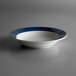 A close up of a Libbey Lunar Bright White Porcelain deep rim bowl with a steel blue band.