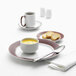 A Libbey Lunar Bright White Porcelain plate with apple butter stripes with soup and bread on it.