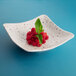 An Elite Global Solutions square melamine bowl filled with raspberries and mint leaves.
