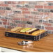 A GET Enterprises Curator metal crate cutting board frame holding food on a table.