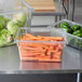 A Rubbermaid clear plastic food storage container full of carrots and lettuce on a table.