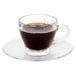 A Libbey glass cappuccino cup on a saucer with coffee in it.