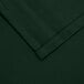 A close up of a hunter green hemmed fabric square.