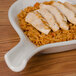 A CAC white fry pan plate with meat and rice on a wood surface.