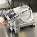 A person using a Hobart HS7-1 automatic meat slicer.
