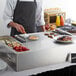 A chef using an Avantco Made-To-Order Pancake Station to cook pancakes on a countertop griddle.