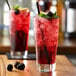 A glass of red Monin Sugar Free blackberry syrup with ice.