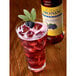 A glass of Monin blackberry lemonade with ice and berries.