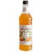 A bottle of Monin Spicy Mango Flavoring Syrup with an orange label and orange liquid.