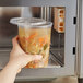 A hand holding a Choice microwavable clear plastic container of soup.