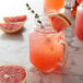 A glass jar with a drink and a slice of Monin Ruby Red Grapefruit Syrup on top.