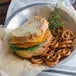 A sandwich with yellow mild cheddar cheese, pretzels, and greens on a plate.