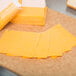 Slices of Great Lakes yellow mild cheddar cheese on a cutting board.