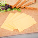 Slices of Cooper sharp yellow American cheese and bread on a cutting board.