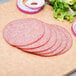 Sliced Magnifico hard salami and onions on a cutting board.