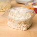 A clear Genpak plastic deli container with coleslaw inside and a high dome lid.