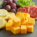 A close-up of yellow Sharp Cheddar cheese cubes on a table.