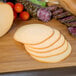 A cutting board with sliced Traditional Delights hickory smoked Gouda cheese and meat.