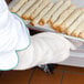 A person using a San Jamar terry sleeve to hold a tray of tortillas.