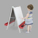 A girl drawing on a Whitney Brothers white easel with dry erase boards.