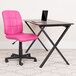 A Flash Furniture pink mid-back office chair next to a desk with a laptop on it.