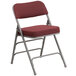 A Flash Furniture burgundy fabric metal folding chair with a metal frame and curved design.