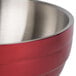 A close up of a red Vollrath beehive serving bowl with a stainless steel handle.