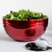 A red Vollrath beehive serving bowl filled with salad on a table.