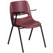 A burgundy plastic chair with a black right handed flip-up tablet arm.