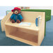 A teddy bear sits on a wooden bench with books in a reading nook.