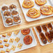 Baker's Mark white non-stick wire rim sheet trays with pastries on a table.