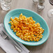 A Tuxton Island Blue oval china platter with macaroni and cheese and a fork.