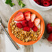 A Tuxton Concentrix papaya fruit dish filled with granola, strawberries, and raspberries.