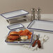 An American Metalcraft rectangular blue speckled melamine serving tray with a burger, fries, and white sauce on a table.